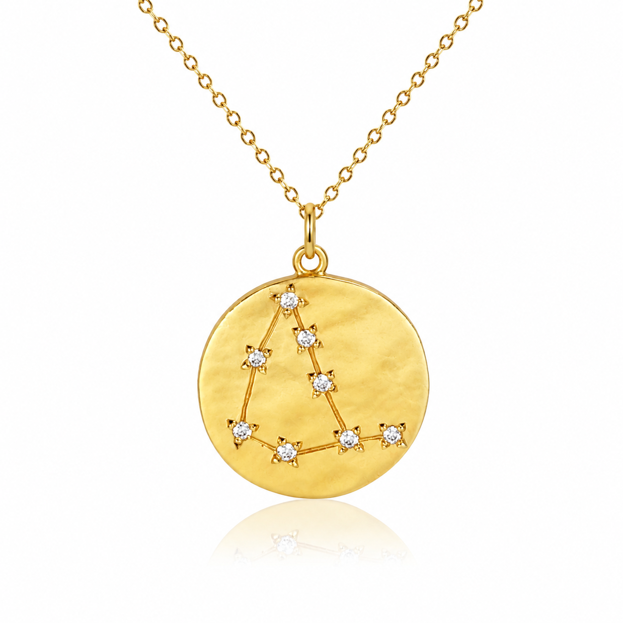 Złota zawieszka inspirowana znakami zodiaku, w której układ kamieni tworzy symboliczne przedstawienie wybranej konstelacji. Okrągła forma zawieszki stanowi tło dla niewielkich diamentów połączonych delikatnymi liniami, odwzorowującymi układ gwiazd charakterystyczny dla danego znaku.